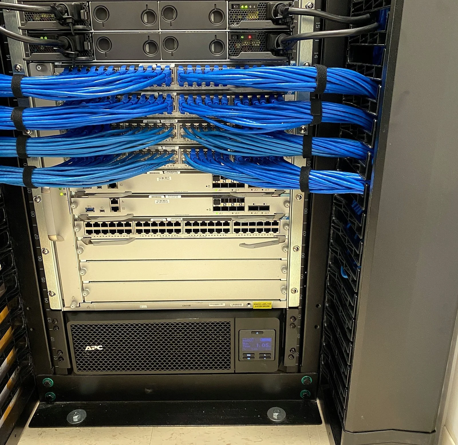 Network rack with blue Cat6 patching above a modular chassis