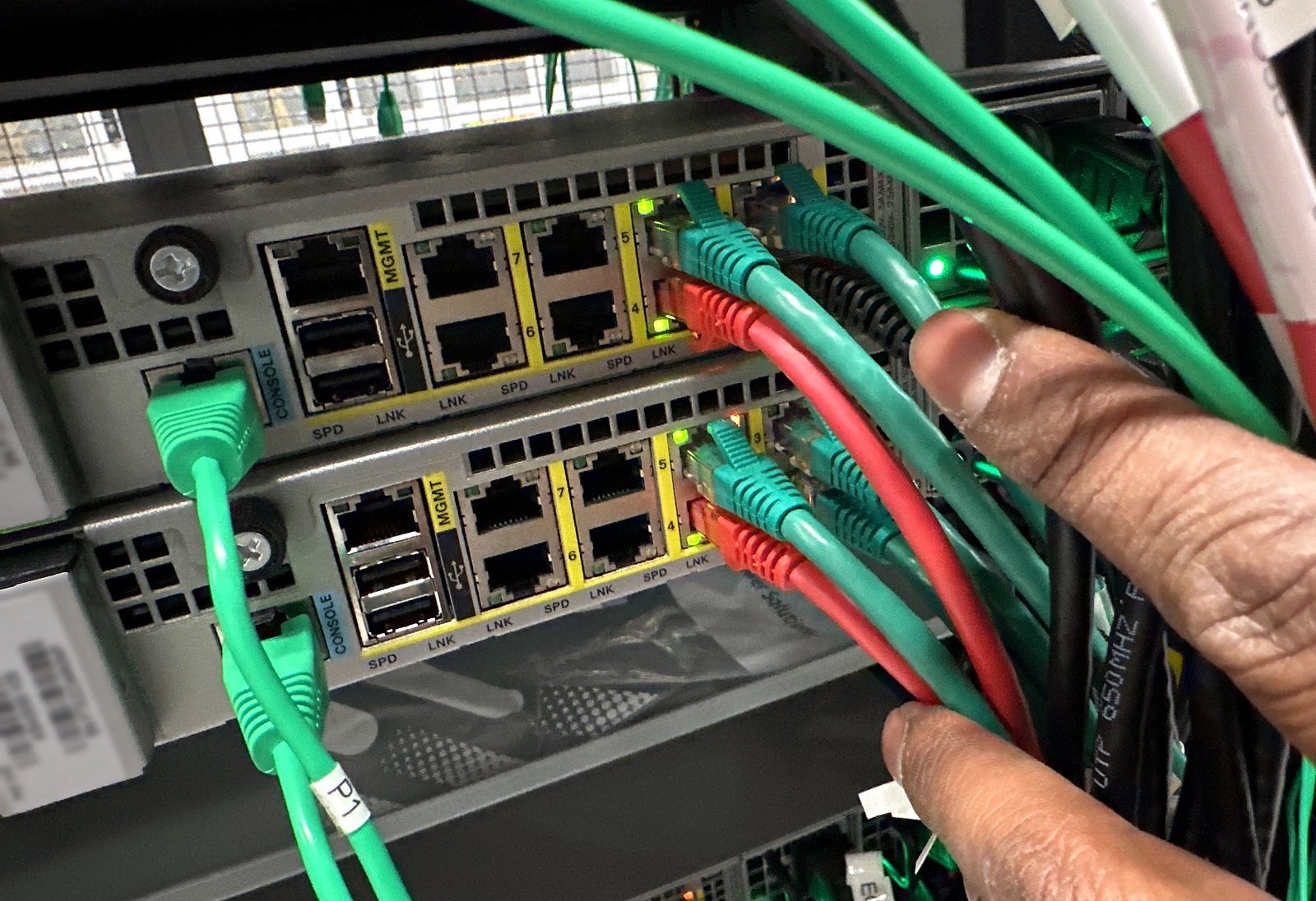 Technician seating green Cat6 patch cables into a switch during a cutover