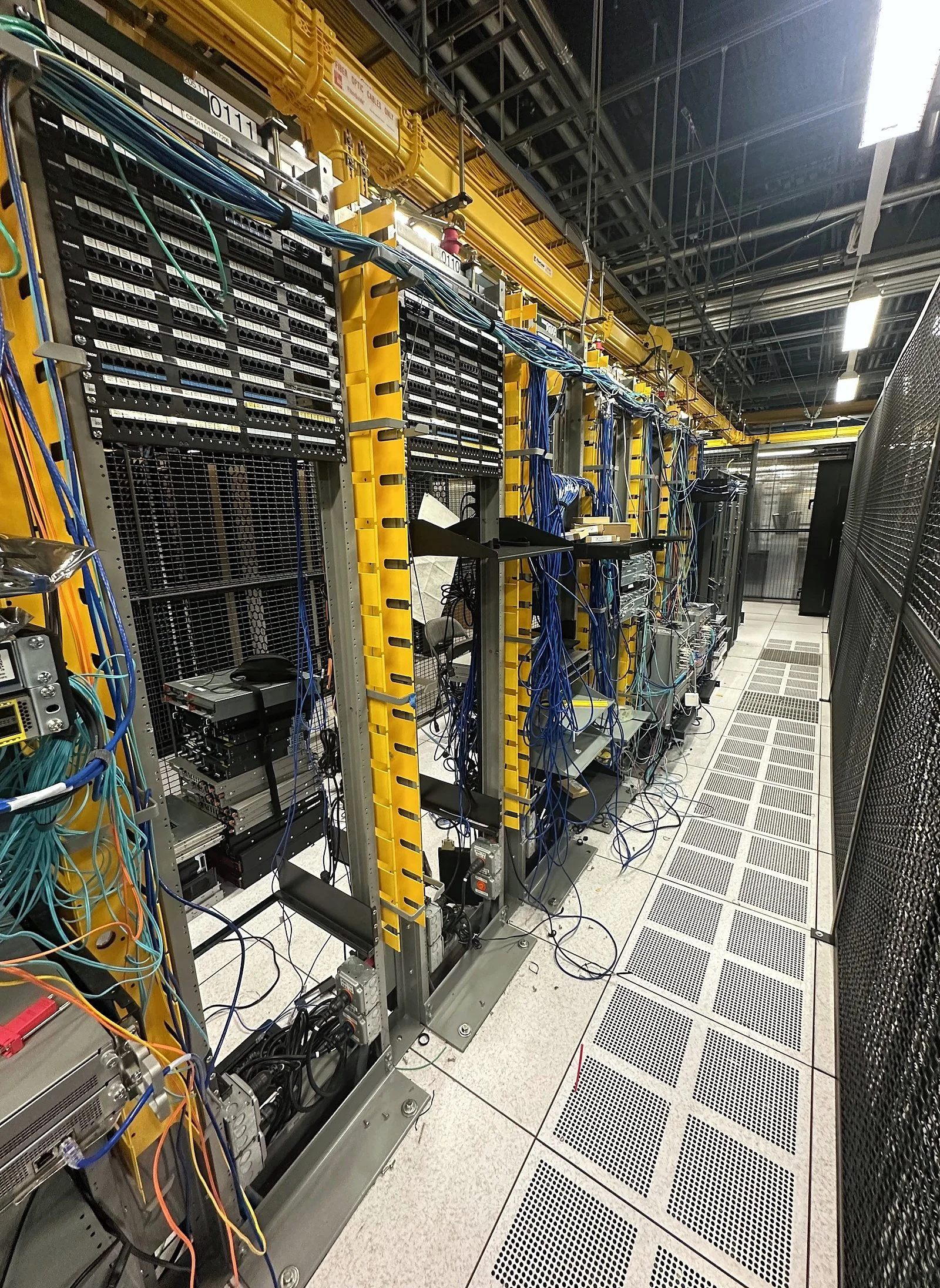 Data center aisle lined with cabinets and overhead raceway