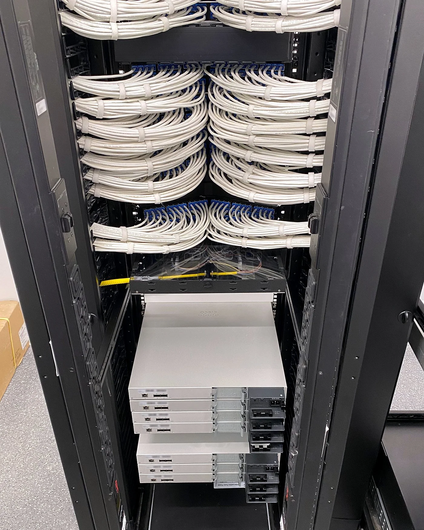 New switches racked under white Cat6 patching during a data center migration