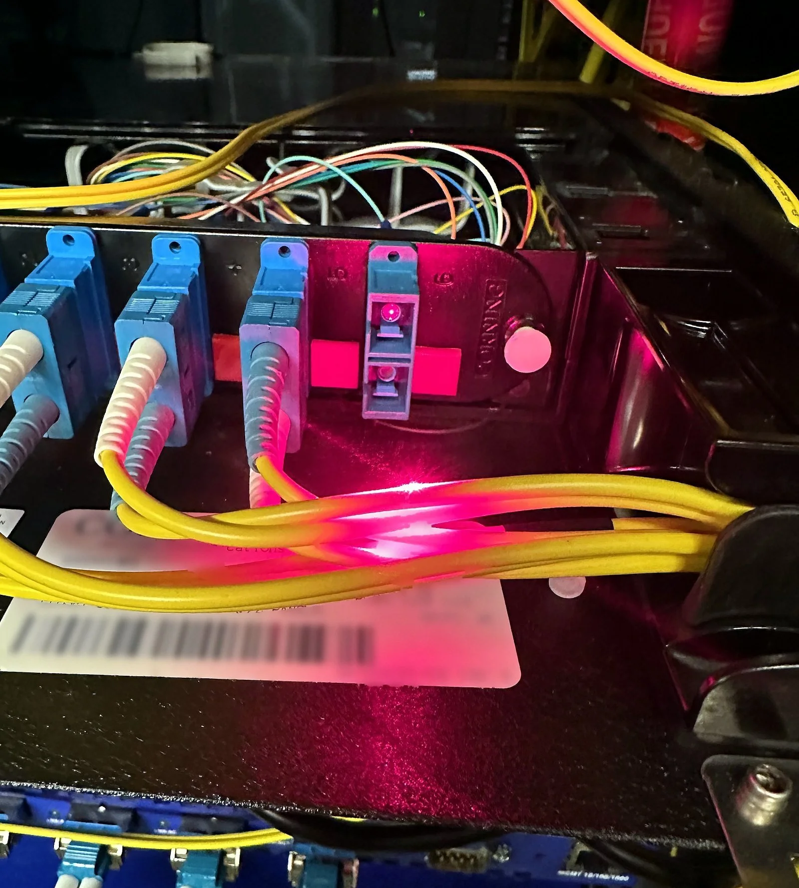 Red visual fault locator light tracing a fiber run on a patch panel