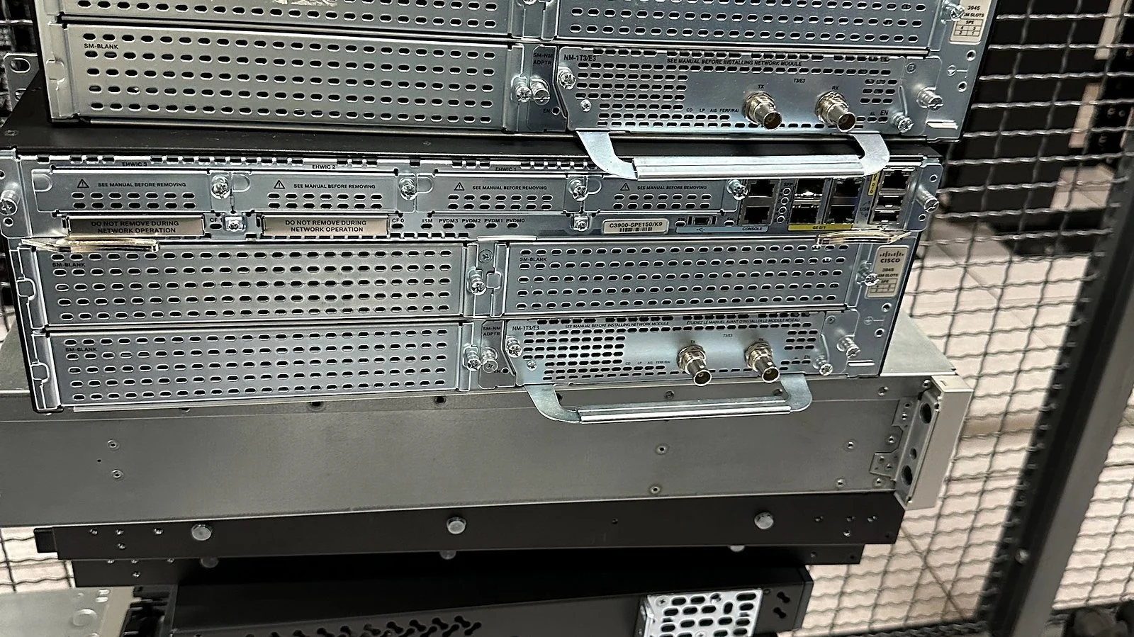 Decommissioned Cisco routers stacked on a cart for removal