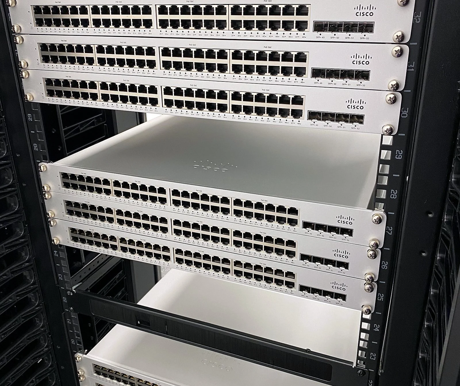 Stack of new switches racked in a cabinet before patching