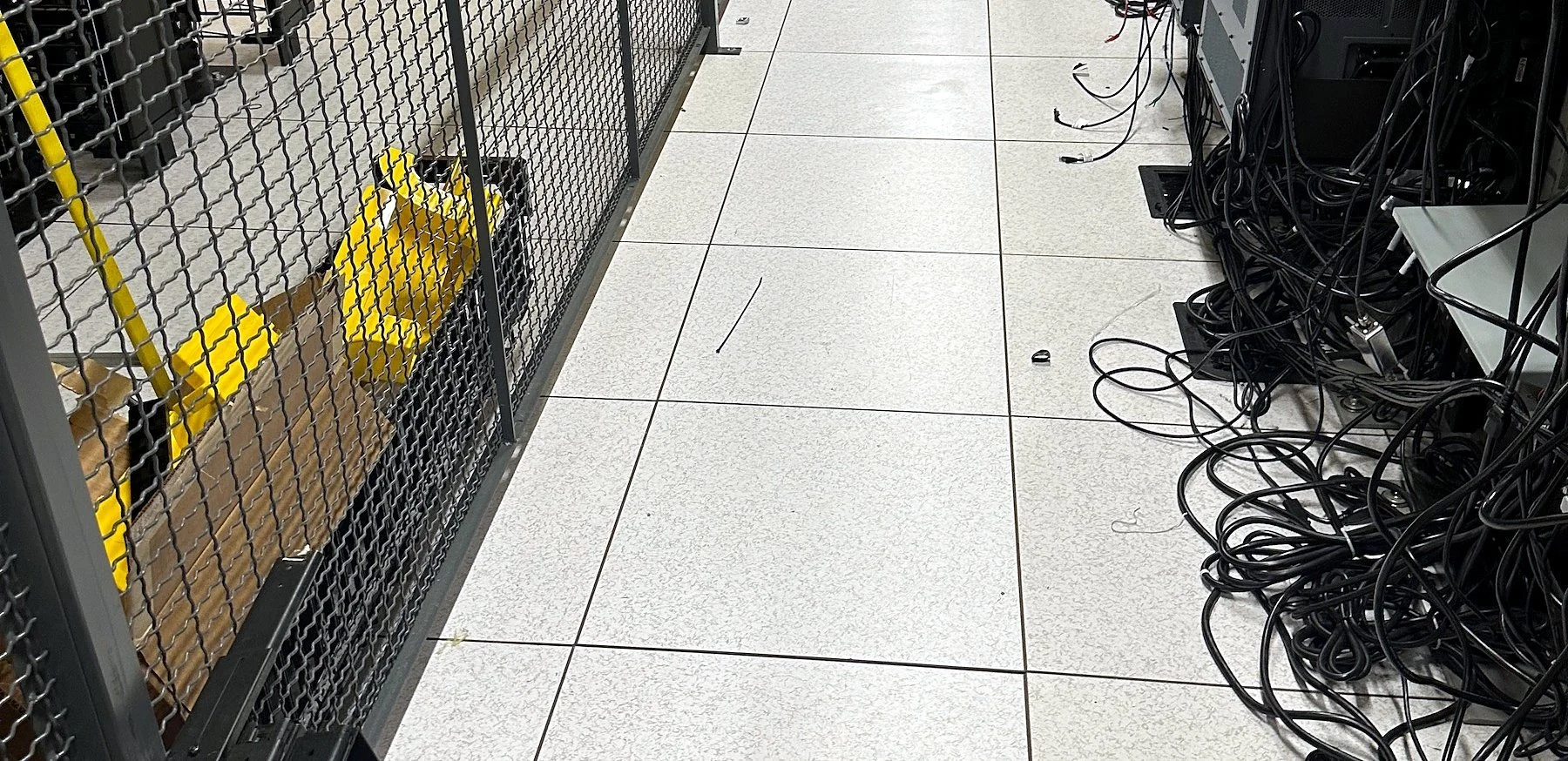 Colocation cage aisle with cabinets and raised floor tiles