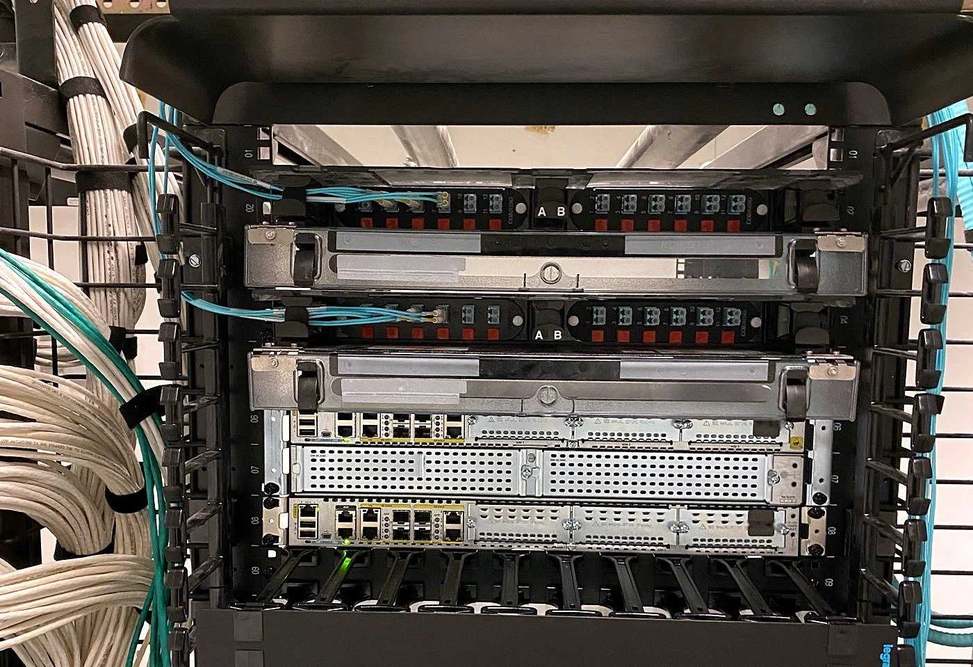 Network rack with Cisco routers, fiber panels and dressed Cat6 cabling