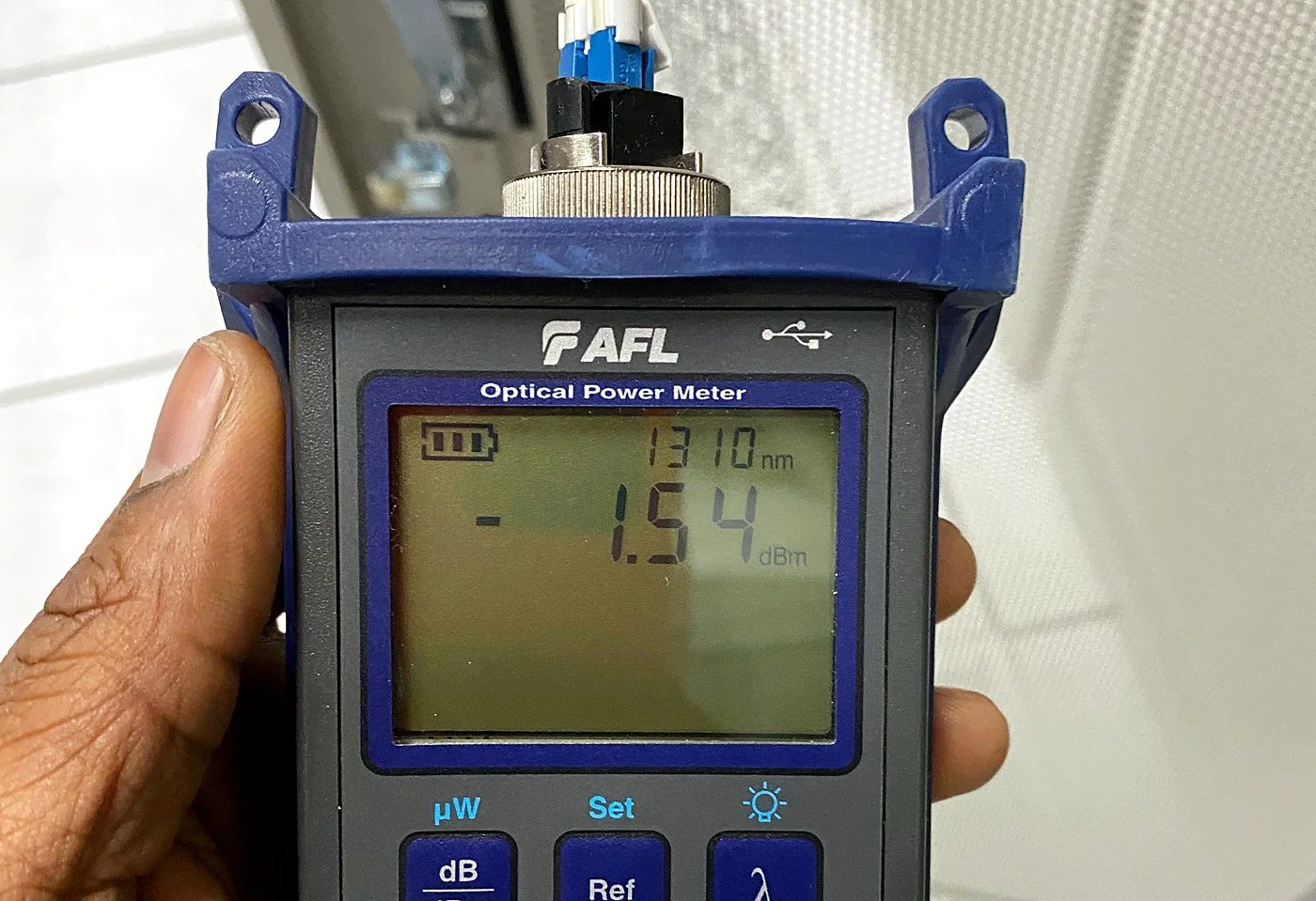 Core-1 technician checking fiber light levels with an AFL optical power meter at 1310 nm