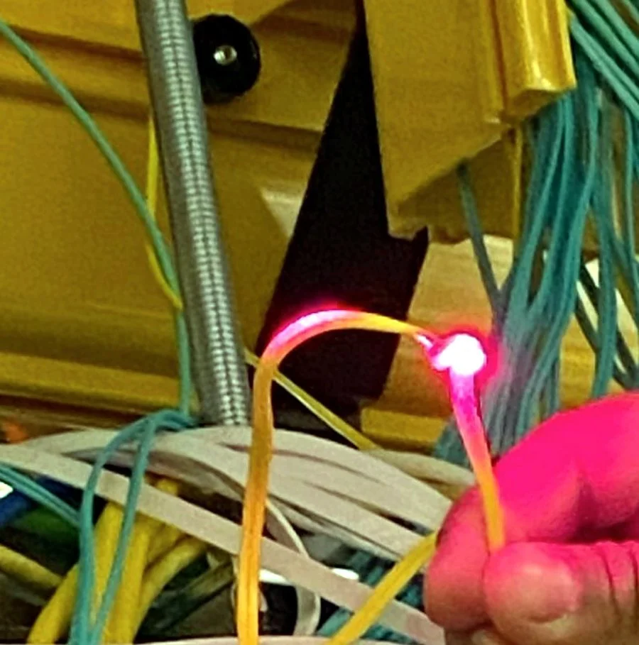 Visual fault locator lighting a fiber patch cord to trace a link in a data center rack