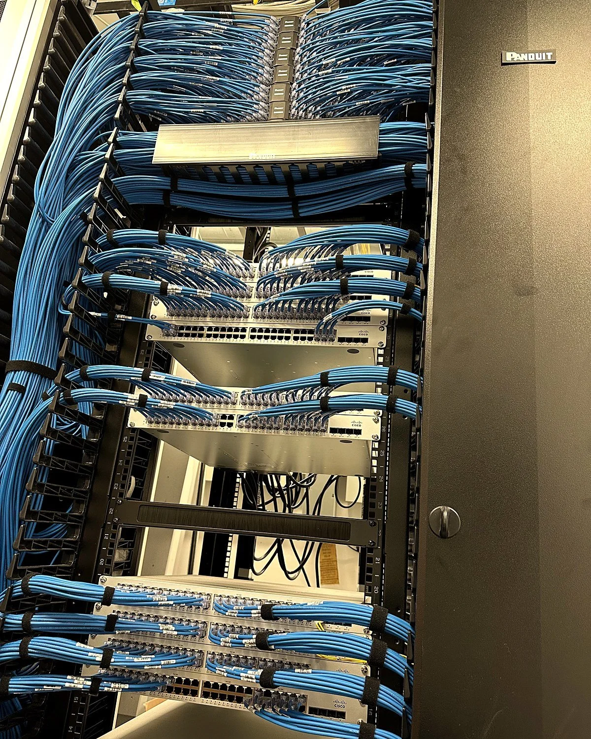 Blue Cat6 patch cables dressed into vertical cable managers in a New York data center rack