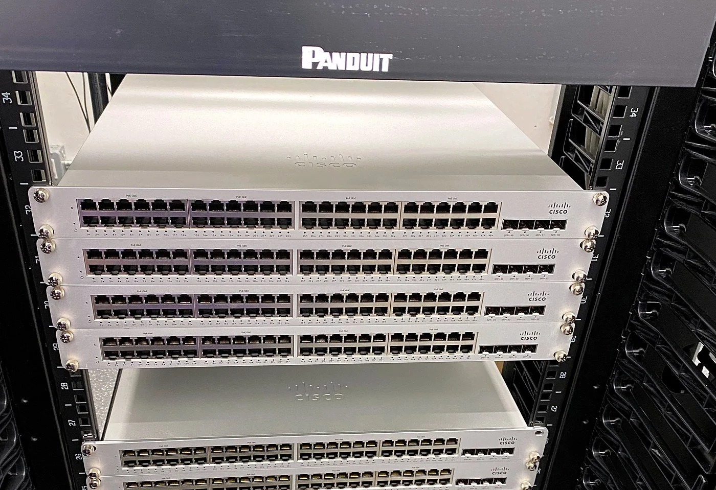 Stack of Cisco access switches racked in a Panduit cabinet before patching