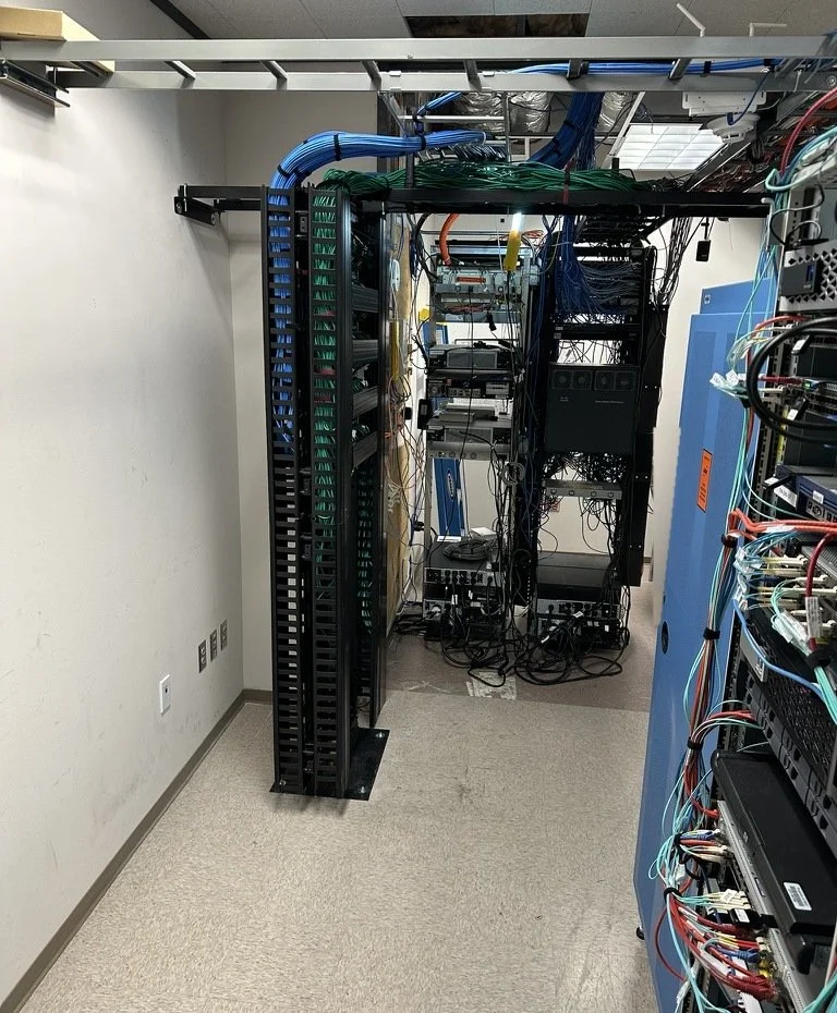 Telecom room with network racks, overhead ladder rack and vertical cable managers