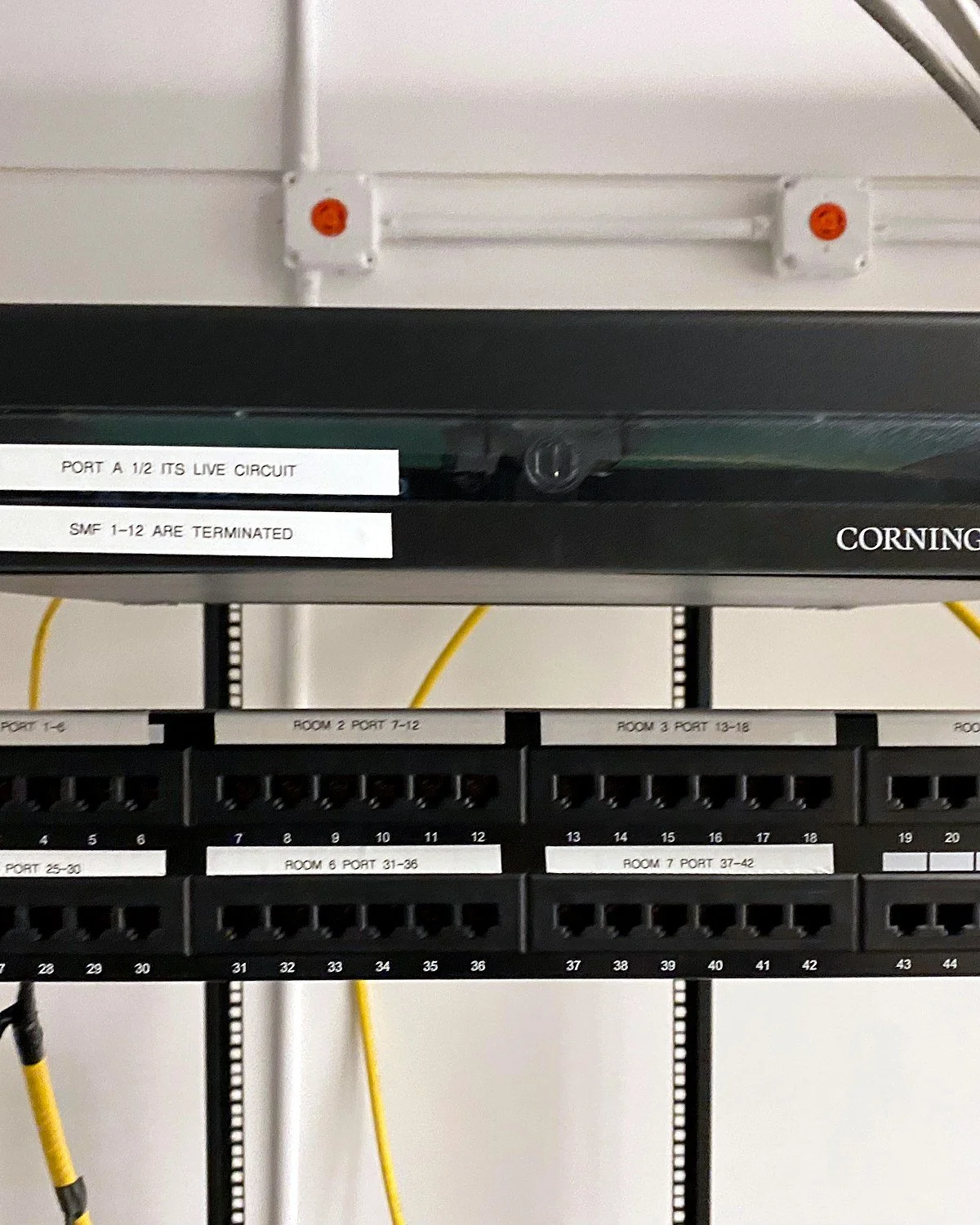 Labeled Cat6 patch panels and Corning fiber enclosure in an office network rack