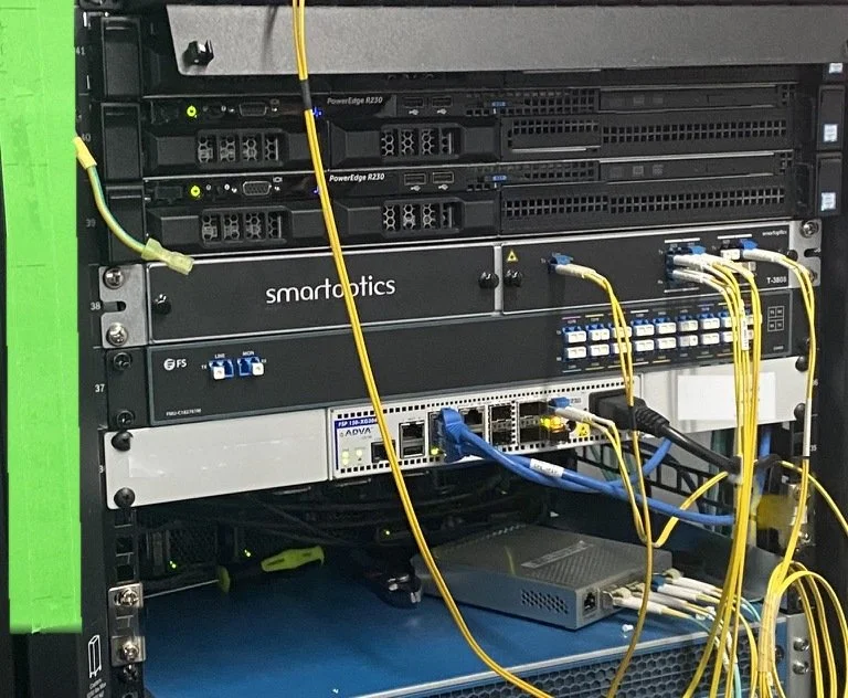 Rack with Dell servers, fiber mux shelves and an ADVA demarc patched with single-mode fiber