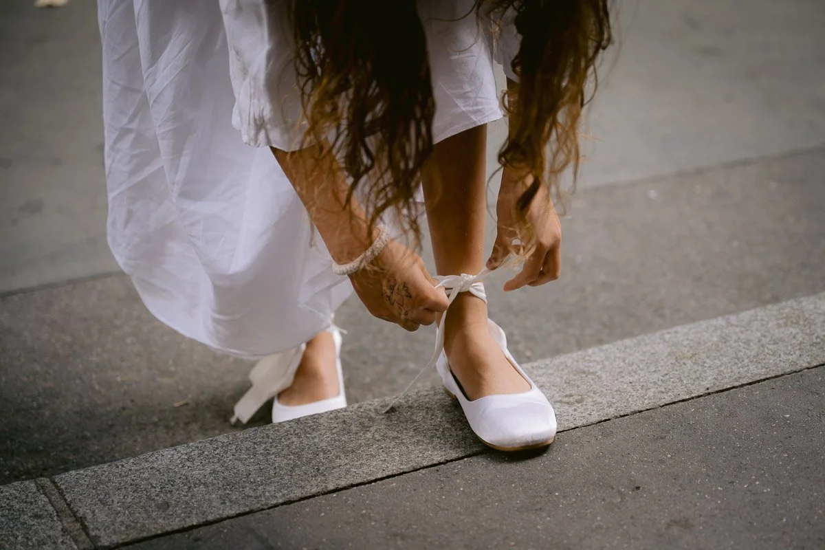 Instant volé et spontané d'une petite fille du cortège refaisant ses lacets. Photographe de mariage indépendant attentif aux petits moments vrais.