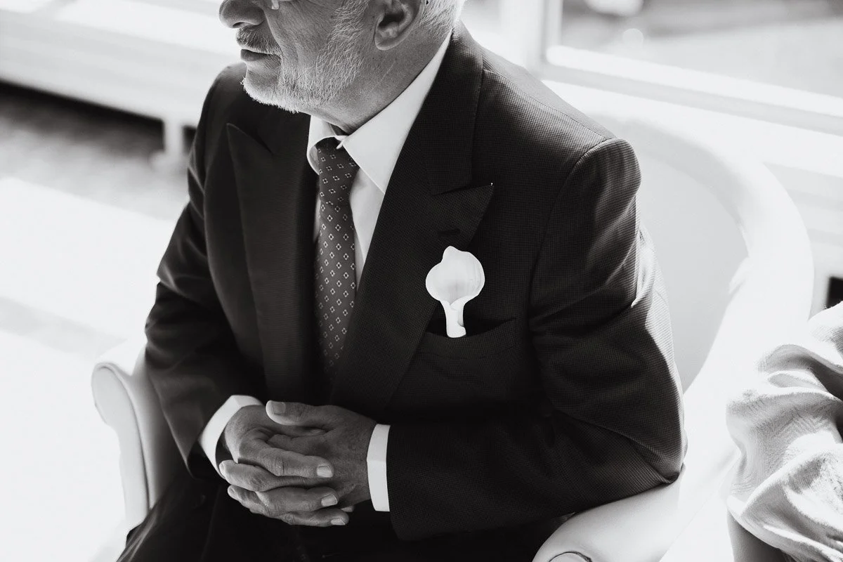 Gros plan sur un détail porté par le père de la mariée. Photographe de mariage attentif aux accessoires et aux invités.
