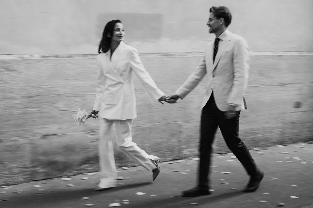 Photographie de reportage : les jeunes mariés marchent main dans la main dans une rue parisienne. Instant décontracté et spontané.