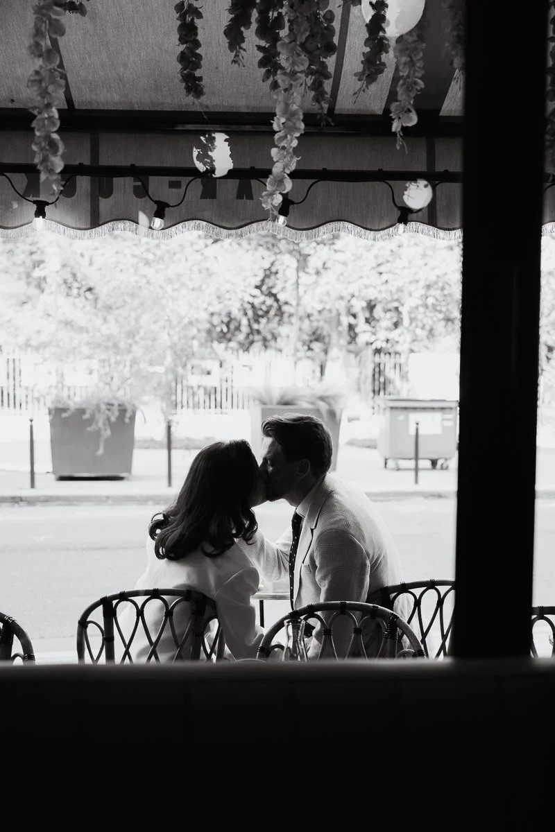 Baiser passionné des jeunes mariés en contre-jour sur une terrasse parisienne. Photo de couple romantique et artistique à Paris.