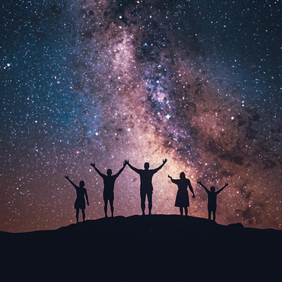 Silhouetten einer Familie mit fünf Personen, die auf einem Hügel stehen und in den Sternenhimmel blicken, mit einer klar sichtbaren Milchstraße im Himmel.