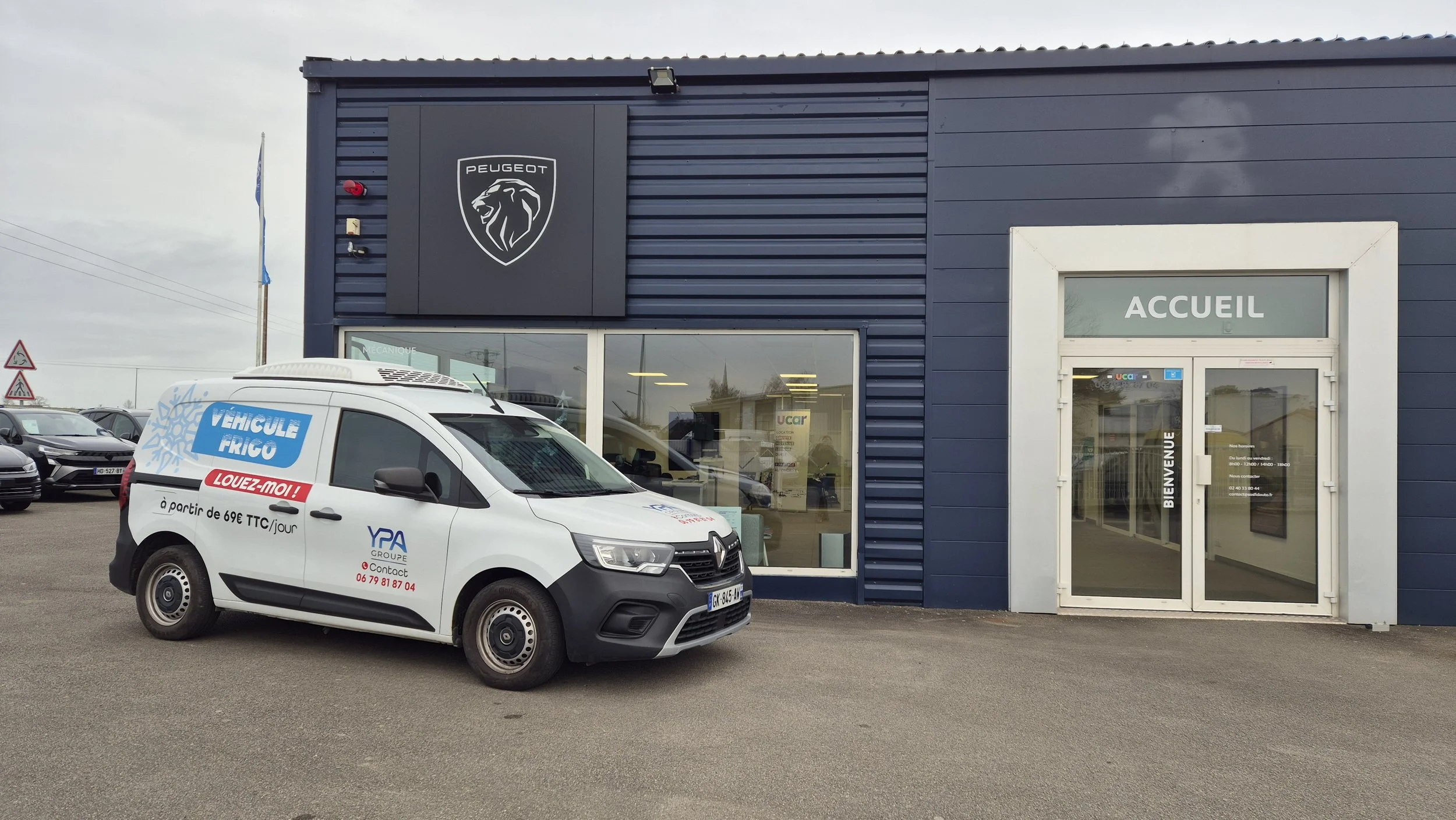 Voiture de location frigorifique stationnée devant un bâtiment Peugeot avec un panneau 'ACCUEIL' à l'entrée. Du Groupe YPA.