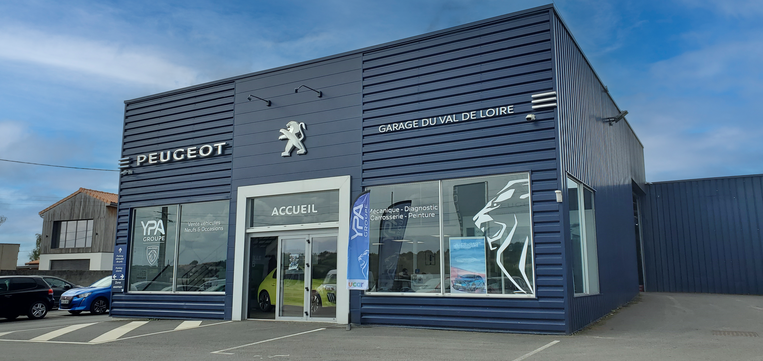 Agent Peugeot avec façade bleue, logo de lion, panneaux d'information et voitures exposées devant l'entrée. GARAGE VAL DE LOIRE