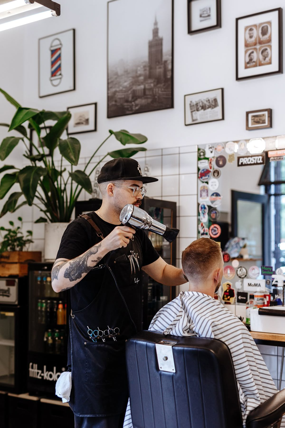 Een kapper droogt het haar van een klant in een kapsalon.