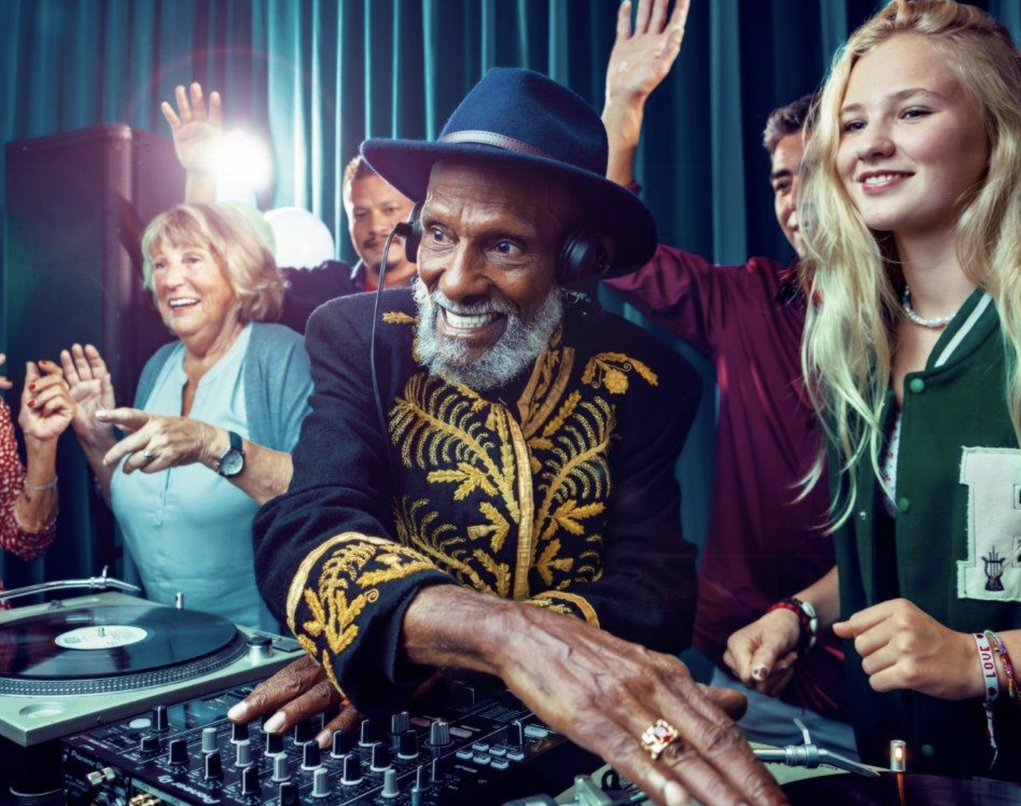 Een groep mensen danst en geniet op een feestje met een DJ die muziek draait, omringd door kleurrijke lichten.