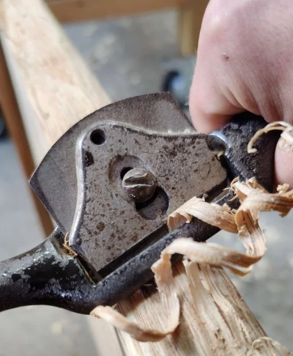 Nahaufnahme eines Handwerkzeuges, das Holz bearbeitet, mit Holzspänen umgeben.
