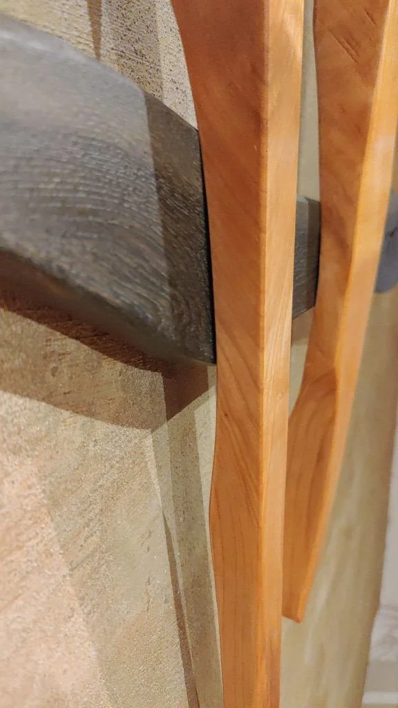 Ein Detailfoto eines Holzrahmens und einer dicken Holzscheibe, die auf einer Steinoberfläche liegt.