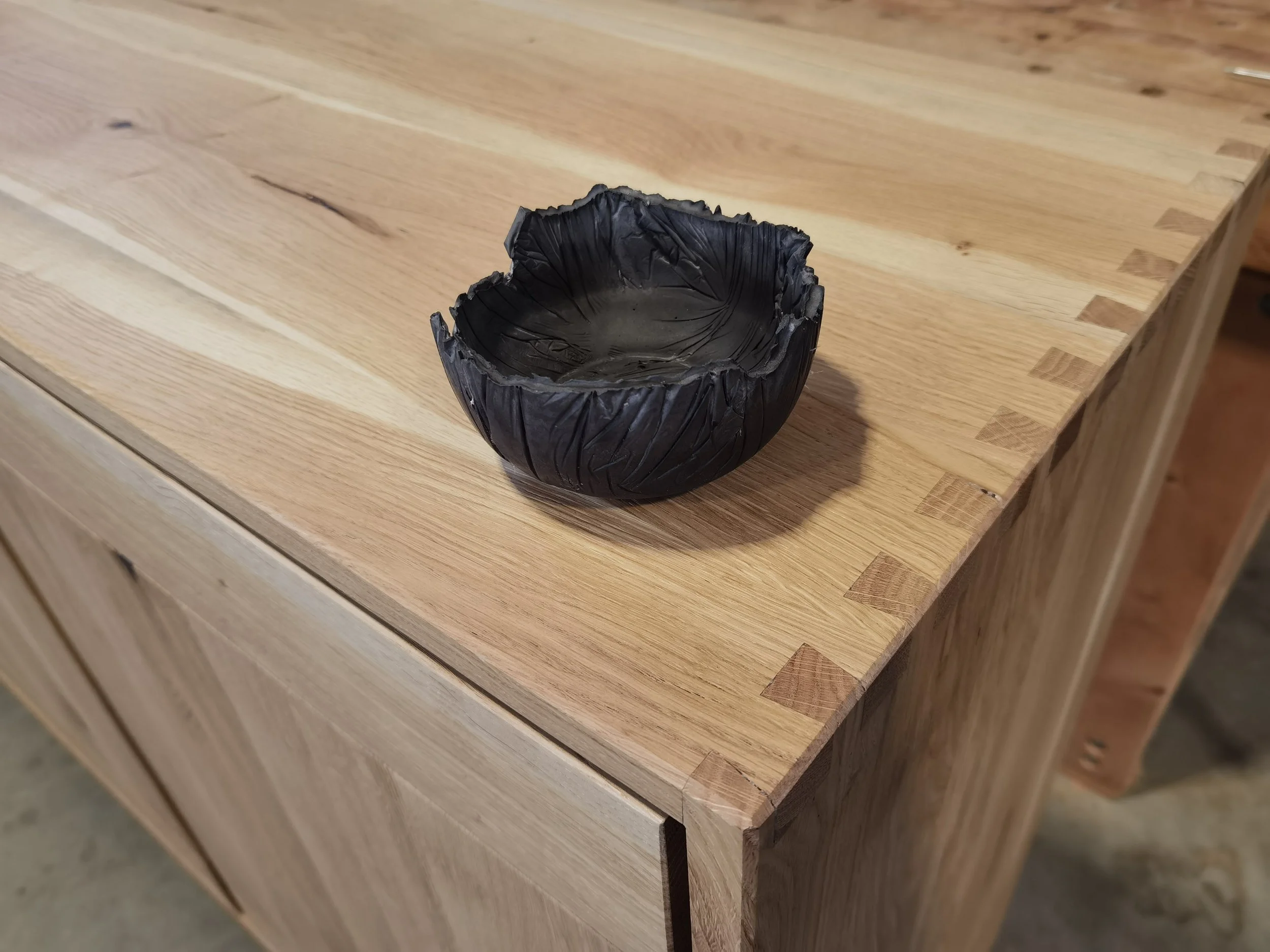 Schwarz gefärbte Keramikschale auf einem Holztisch.