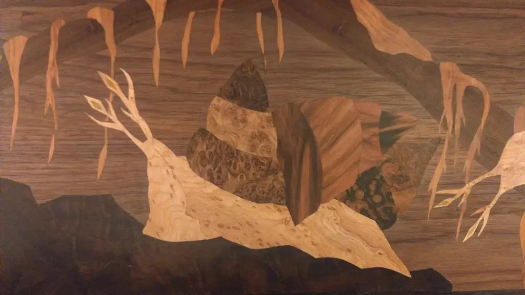 Holzarbeit mit einem Hirschkopf und Blättern aus verschiedenen Holzarten.