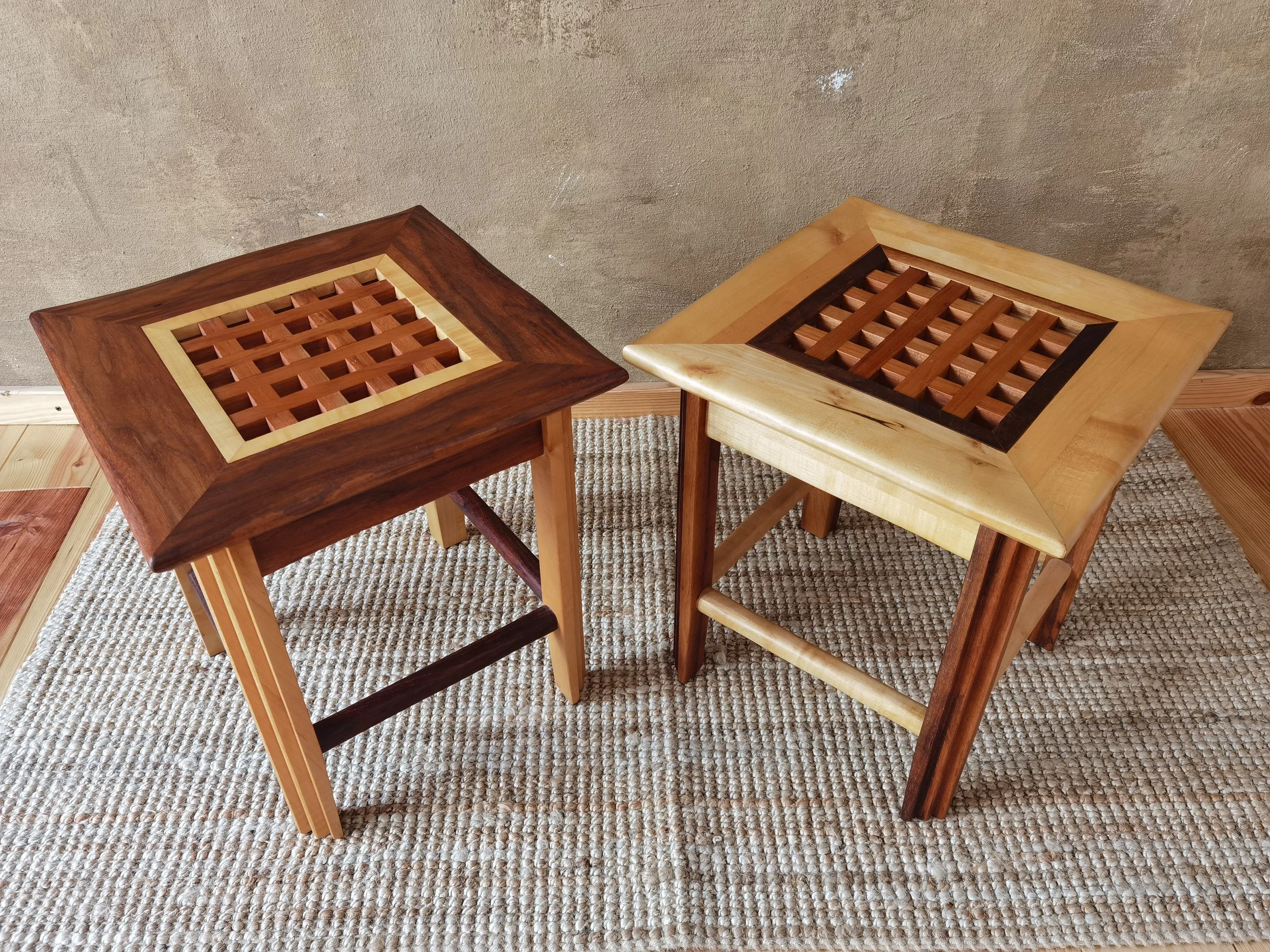 Zwei Holzhocker mit wechselndem Holzdesign und Flachgewebe auf einem Teppichboden.