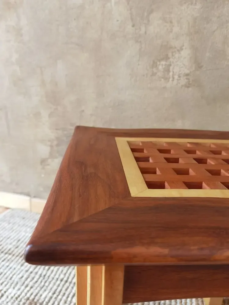 Holztisch mit einer Lamellenmatrix auf der Oberfläche, in einem minimalistischen Raum.