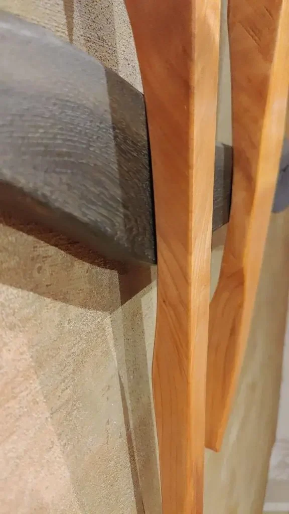 Nahaufnahme eines Holzrahmens, der an einer Wand befestigt ist, mit einem schwarzen Metallstück in der Mitte.