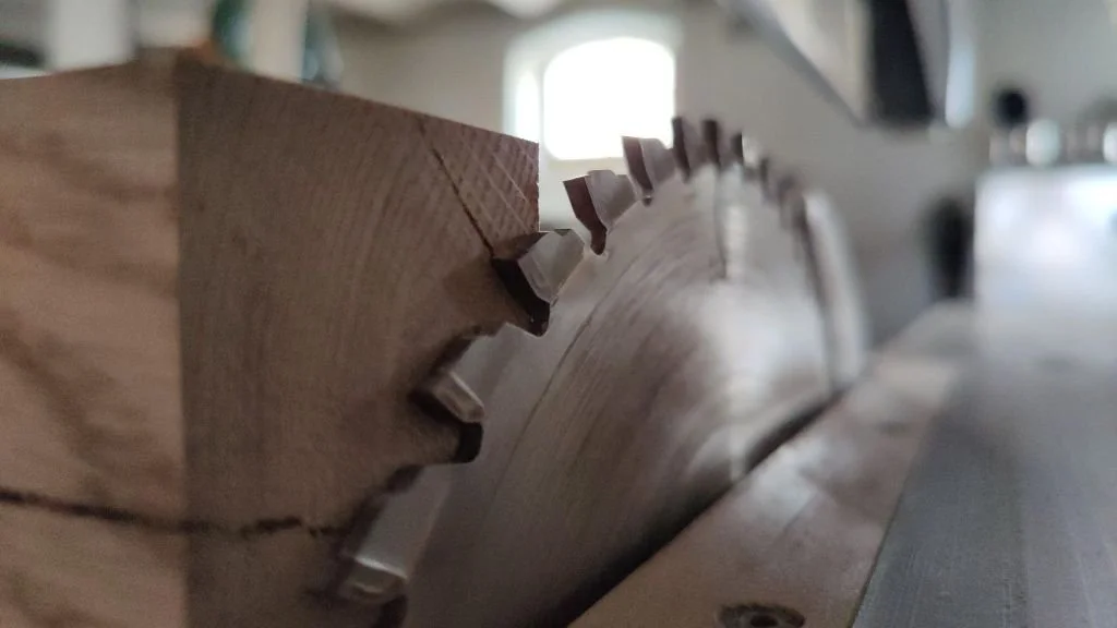 Nahaufnahme eines Holzbalkens mit einer Säge, die auf dem Holz liegt.