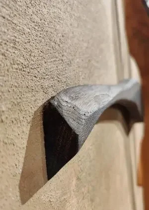 Nahaufnahme eines schwarzen Handwerkzeugs, das gegen eine beige Wand lehnt.