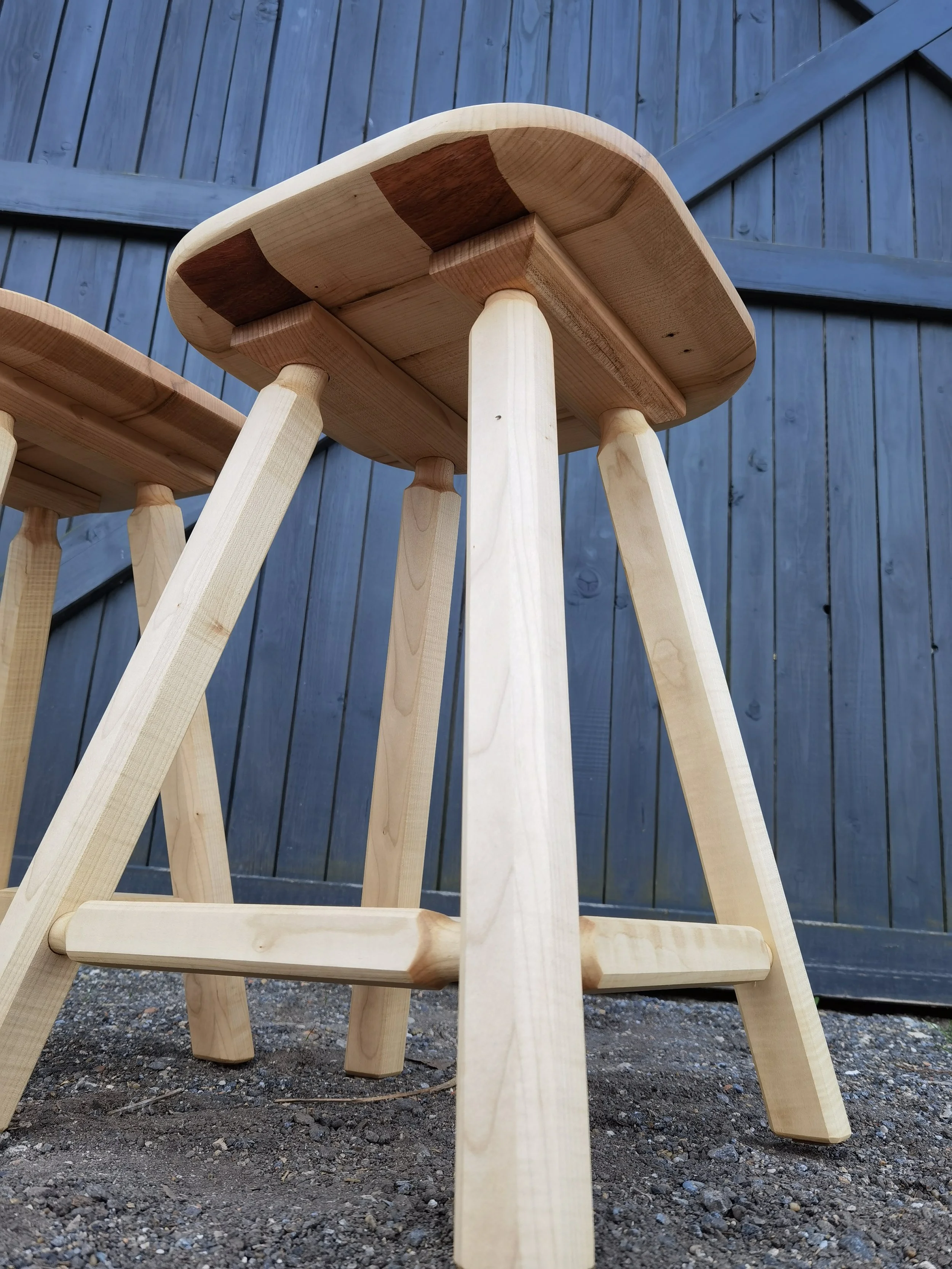 Holztisch mit vier Beinen vor einer blauen Holztür im Freien.