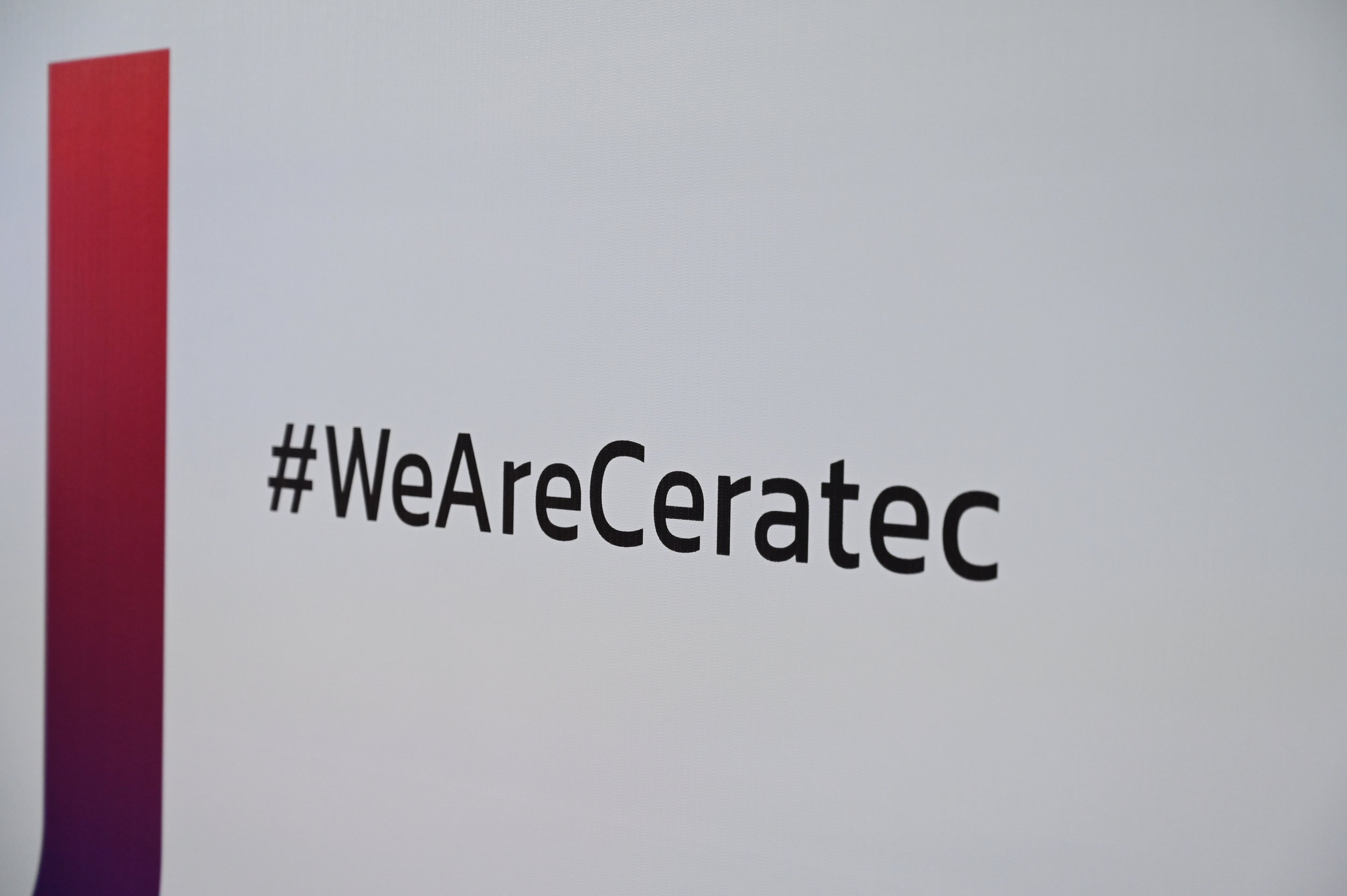 A computer screen displaying the hashtag #WeAreCeratec in black text on a white background, with a vertical red and purple gradient bar on the left side.