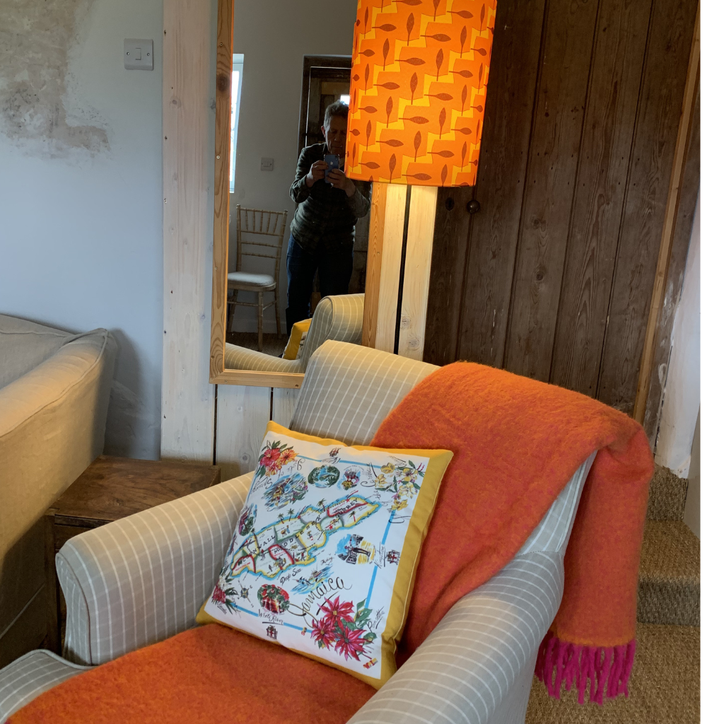 Armchair with colourful throw and vintage lamp behind