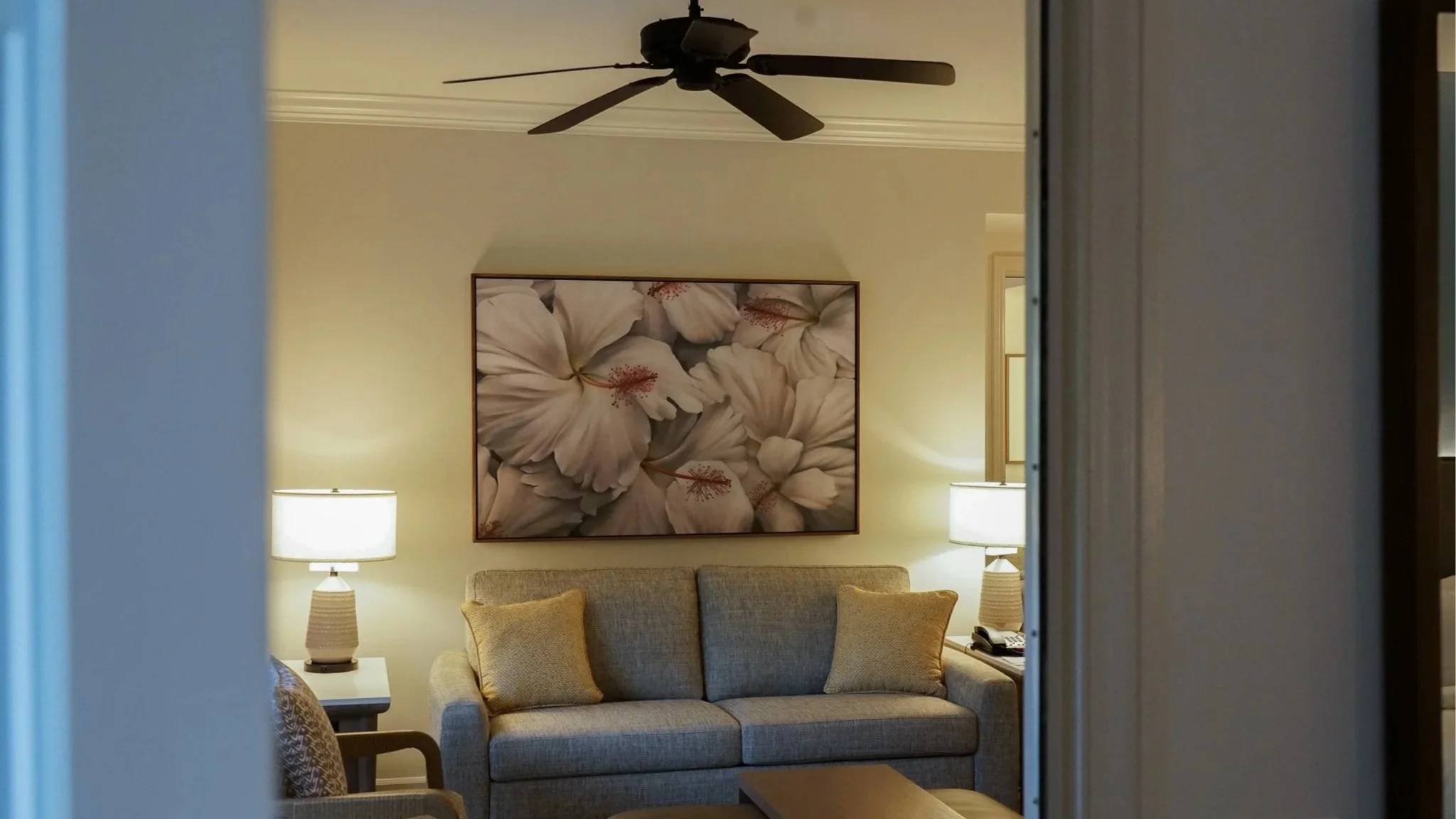 A large botanical oil painting hanging about a sofa.