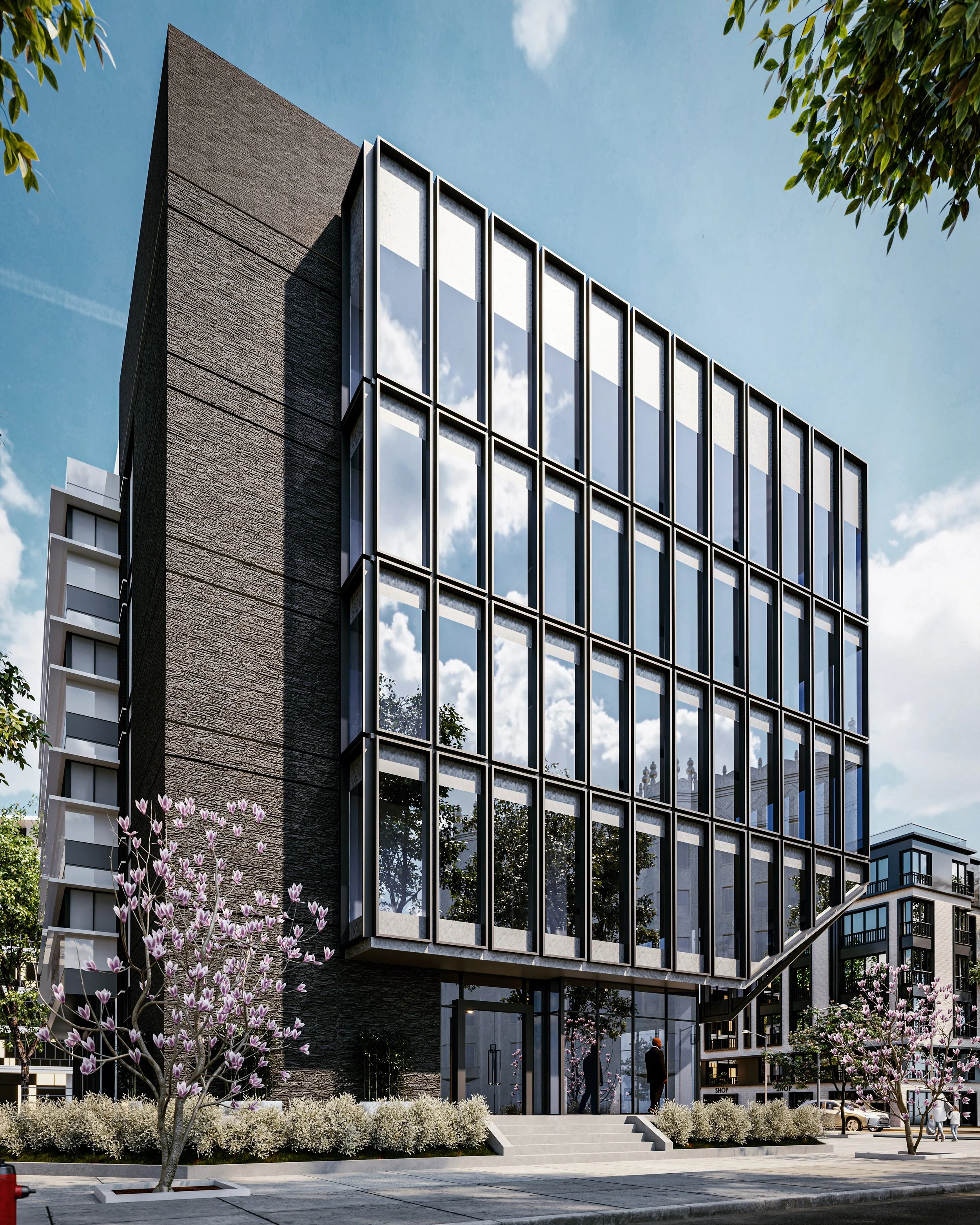 Imagem de um prédio moderno com fachada de vidro, árvores de flores roxas e pessoas na calçada.