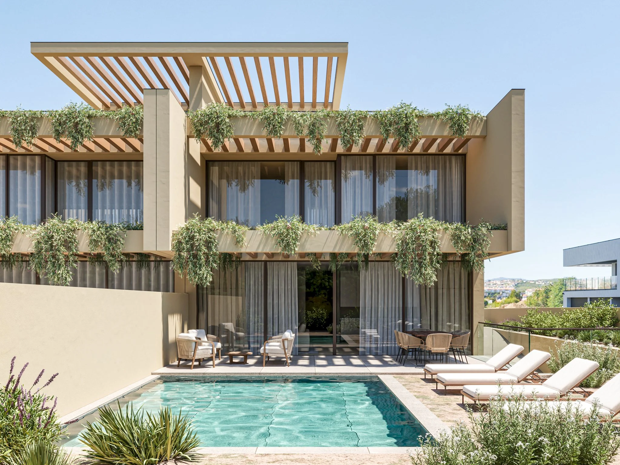 Edifício moderno com varanda, cercado por plantas penduradas, com piscina na área externa com espreguiçadeiras e cadeiras.