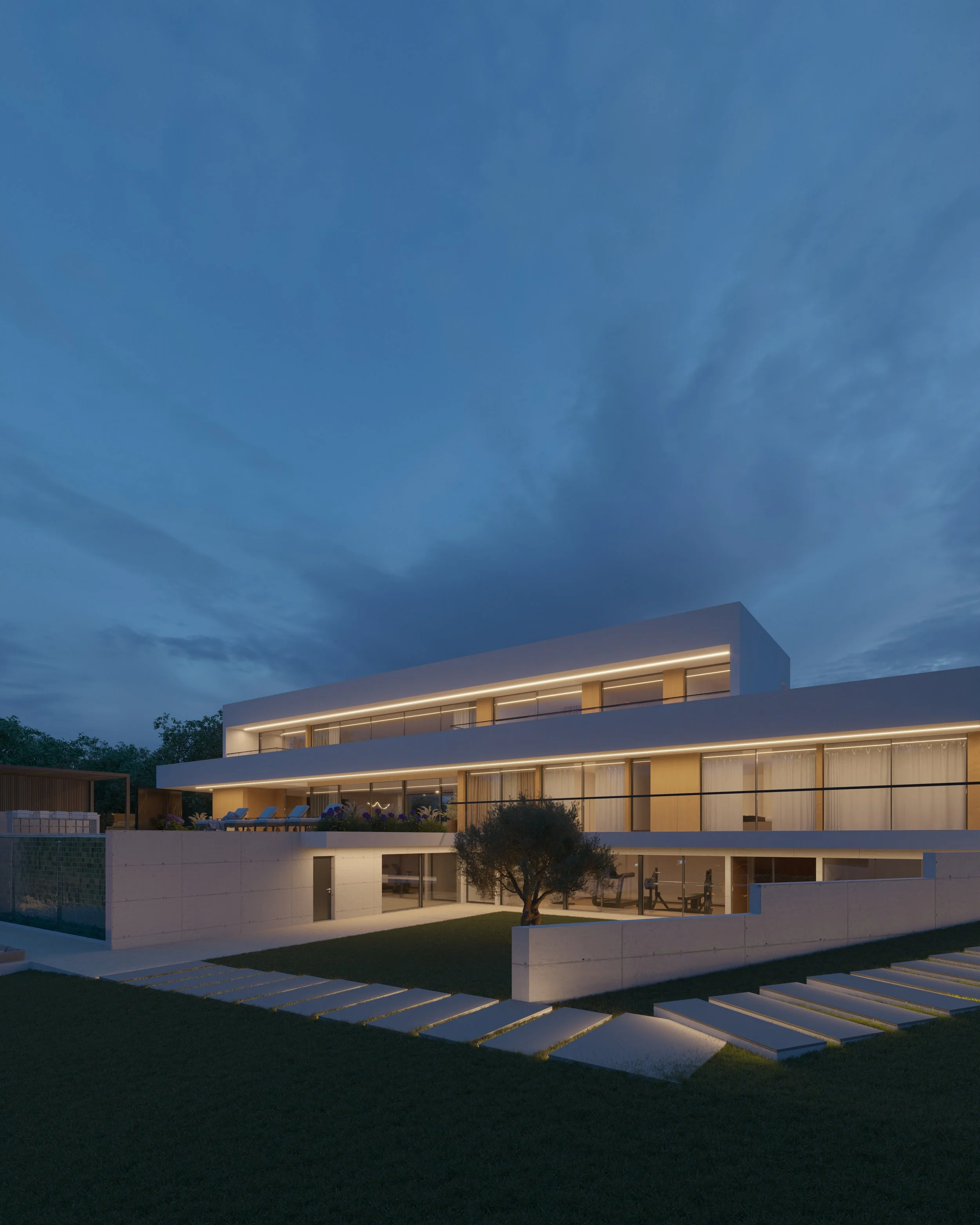 Edifício moderno de três andares com varandas iluminadas e jardim com árvore ao entardecer.