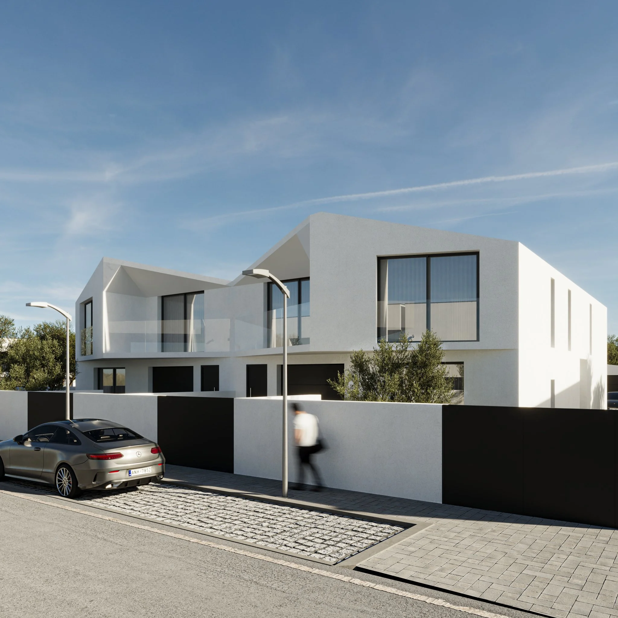 Visualização de uma residência moderna de cor branca com janelas grandes, cercada por um muro preto e branco. No passeio, há um carro cinza estacionado e uma pessoa caminhando, com céu claro ao fundo.