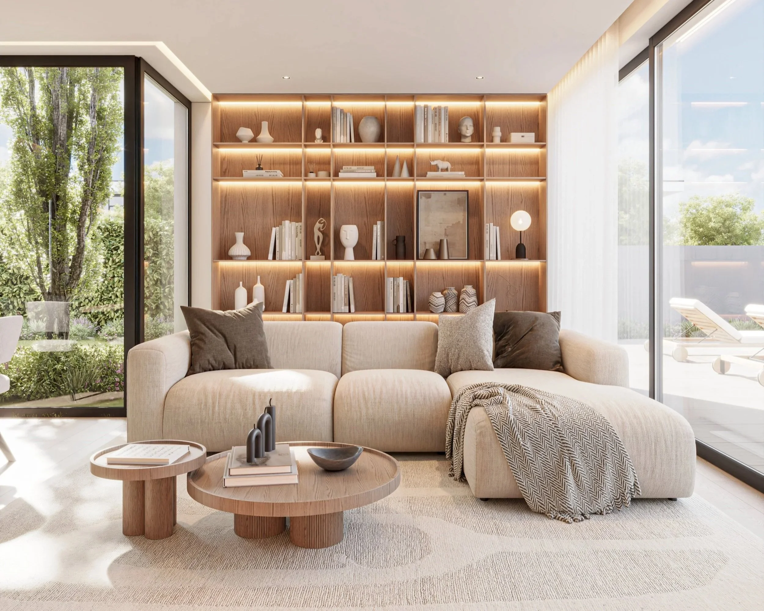 Sala de estar com sofá grande, mesa de centro de madeira, estante de livros de madeira com luminária, e janelas com vista para jardim.