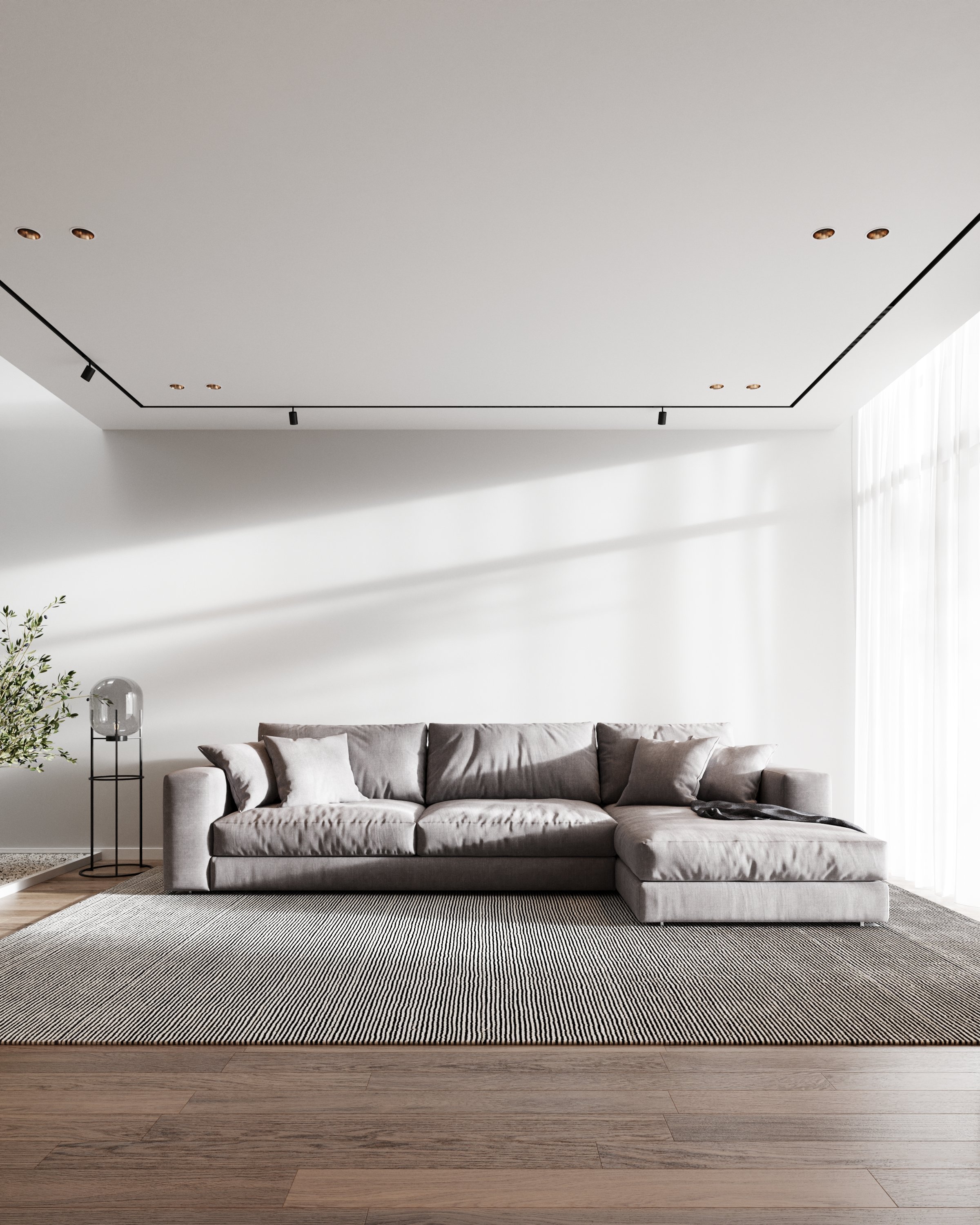 Sala de estar com sofá cinza, tapete listrado, luminária de vidro ao lado e cortinas brancas, ambiente minimalista e bem iluminado.