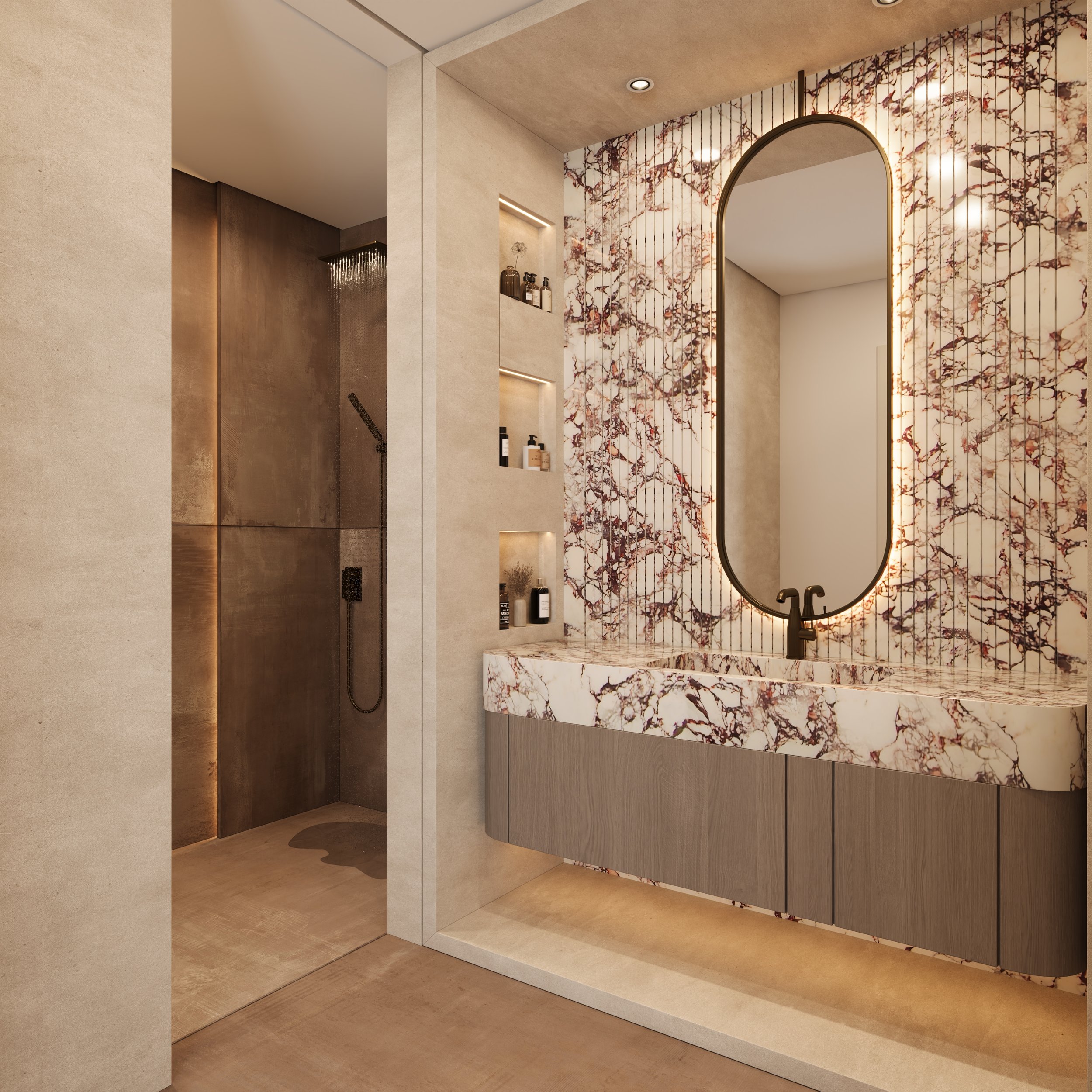 Espelho grande com iluminação embutida ao lado de uma pia de mármore com acabamento de madeira de tonalidade cinza, parede decorada com mármore com padrão de galhos de árvores ao redor, e no canto uma área de banho com parede de vidro e ducha.