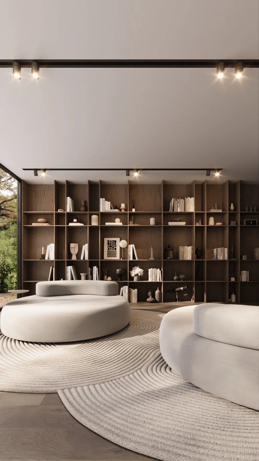 Sala de estar moderna com móveis brancos arredondados, tapete bege com padrão de círculos, e parede de estantes de madeira com livros e objetos decorativos, ao lado de uma janela grande com vista para árvores.