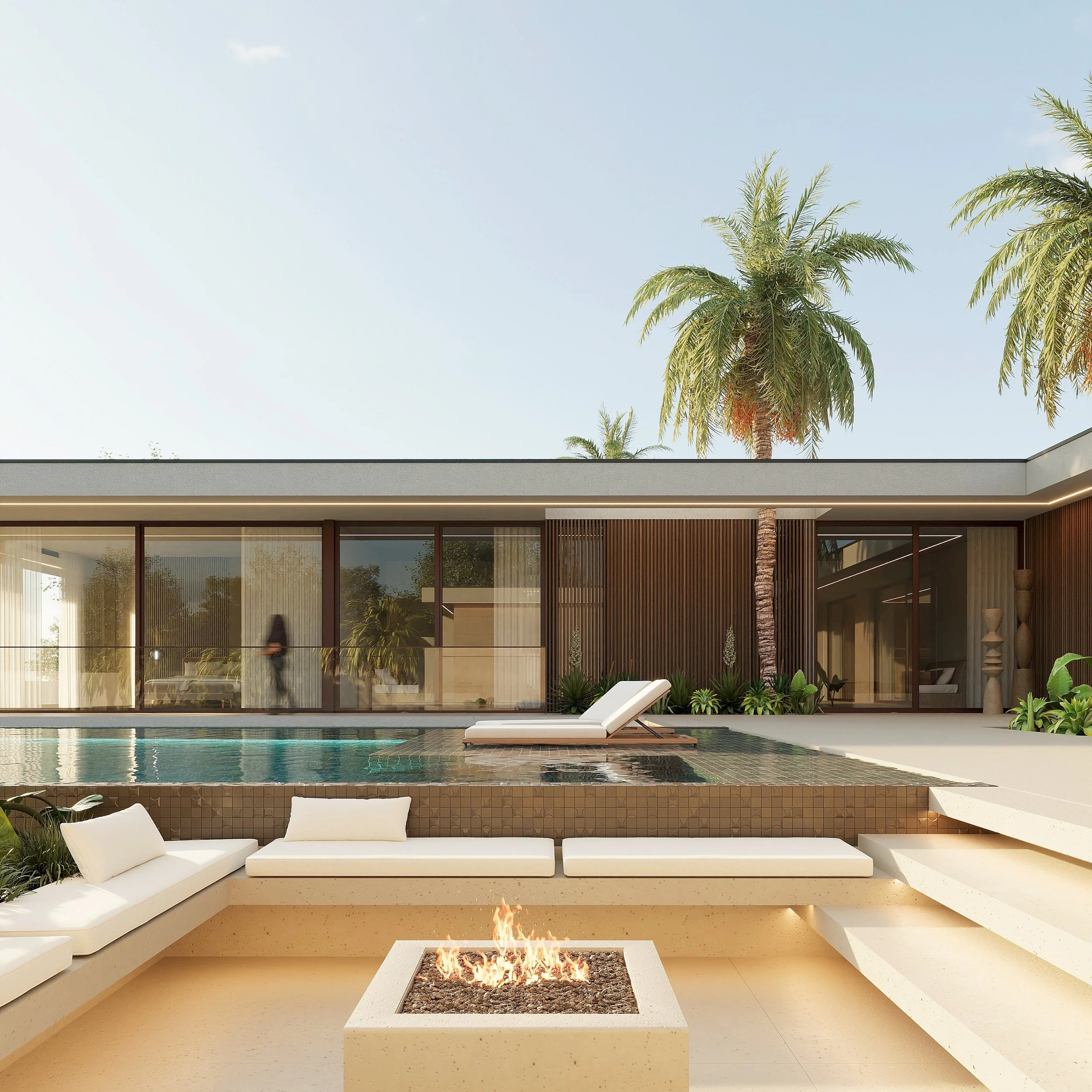 Piscina com espreguiçadeiras brancas e lareira ao ar livre em uma área de lazer ao lado de uma casa moderna de vidro e madeira, com árvores palmadas no fundo.