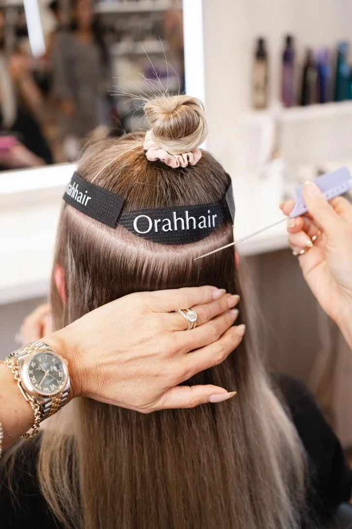 Close-up of an Invisible Bead Extensions (IBE) install using the Orahhair line, silicone-lined beads clamping the wefts to natural hair at Alexandra Siles Salon