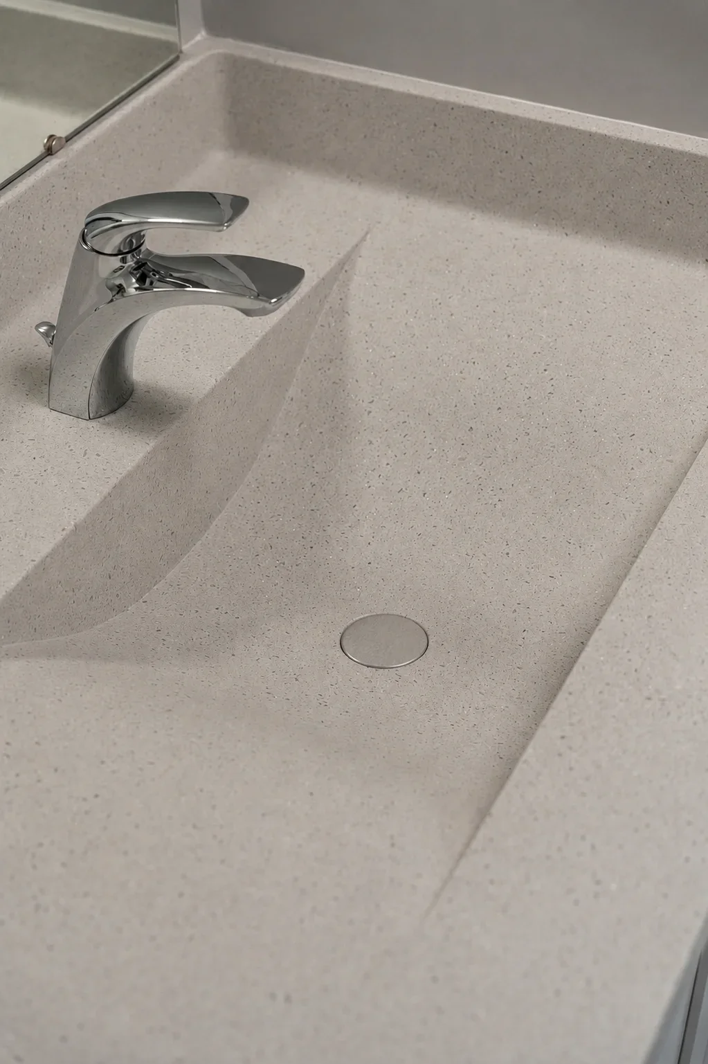 A beige bathroom sink with a shiny silver faucet and a round metal drain.