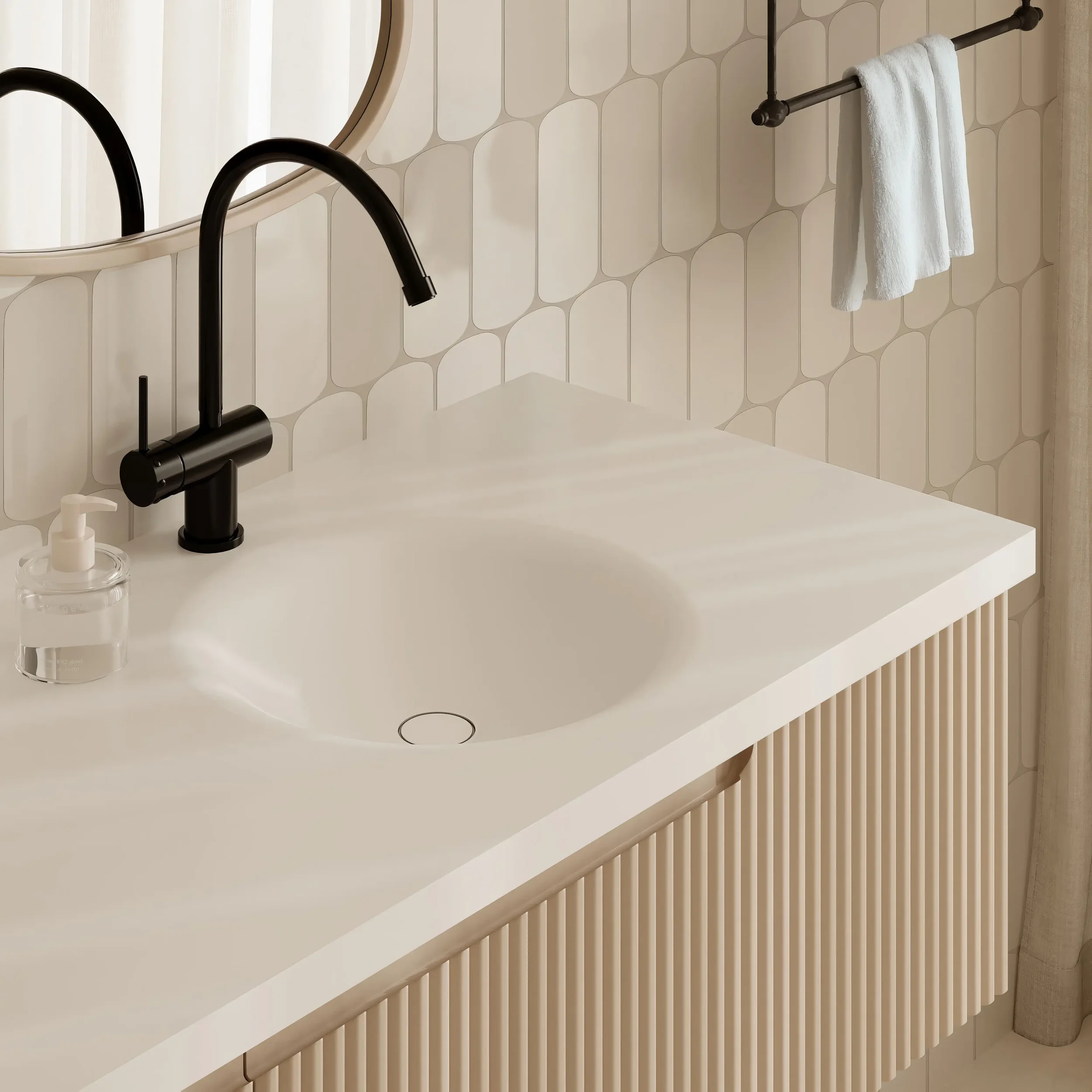 Close-up view of a modern kitchen sink with a black faucet, a soap dispenser, a glass jar, and a white countertop. The background features a decorative tile wall with a circular pattern and a round mirror.